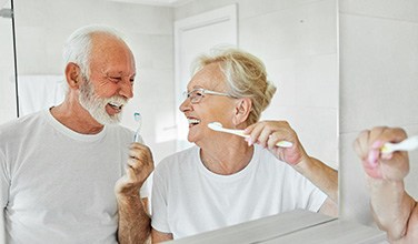 Senior couple smiling while brushing their teeth