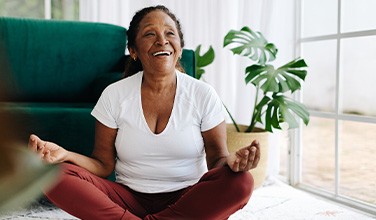 Senior woman smiling while meditating at home