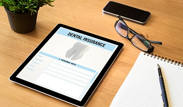 Dental insurance form on tablet next to notepad