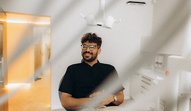 Patient with black glasses smiling in treatment chair