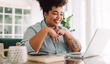 Woman smiling while working on laptop at home