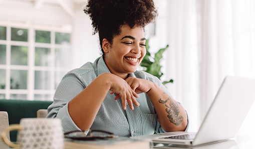 Woman smiling while working on laptop at home