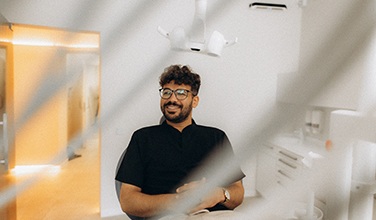Patient with black glasses smiling in treatment chair