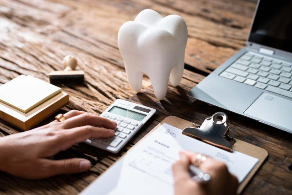Person working on an insurance form on desk with a laptop, calculator, and big tooth paperweight