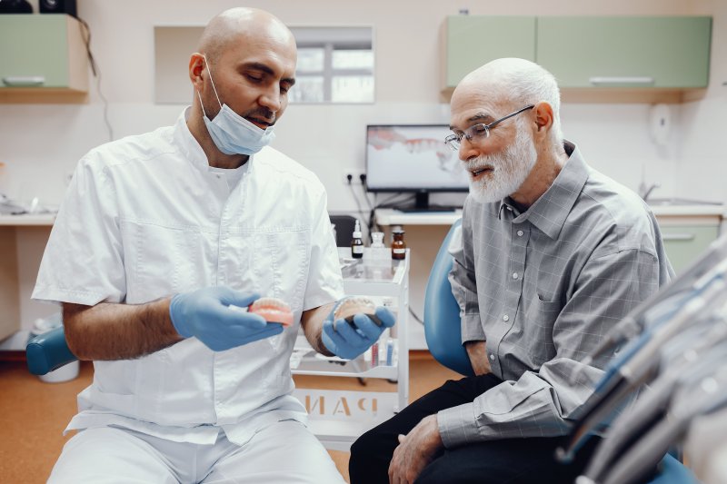 Older man talking with dentist about dental implants